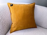 Ein gelbes Kissen auf einem weißen Sofa.