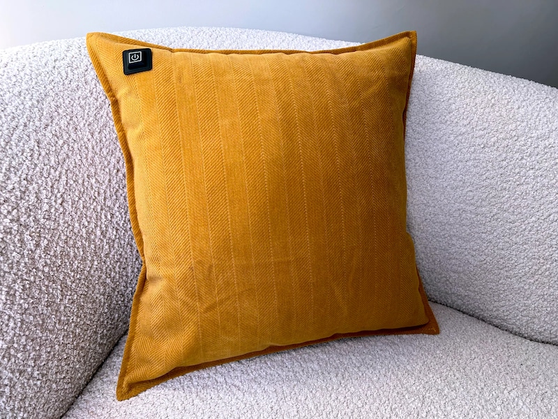 Ein gelbes Kissen auf einem weißen Sofa.