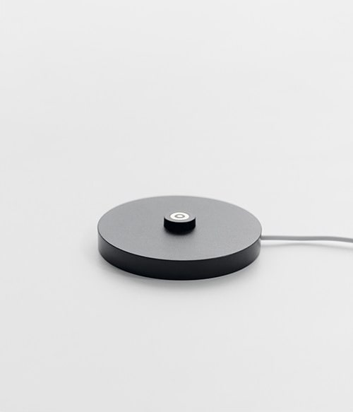 Ein runder, schwarzer Lampensockel mit Kabel.
