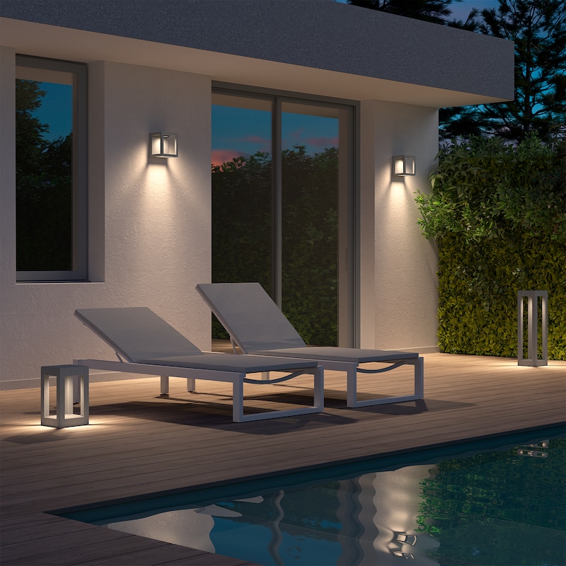 Dos tumbonas junto a una piscina con iluminación exterior.