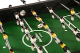 Ein Tischfußballspiel mit gelben und weißen Spielern.