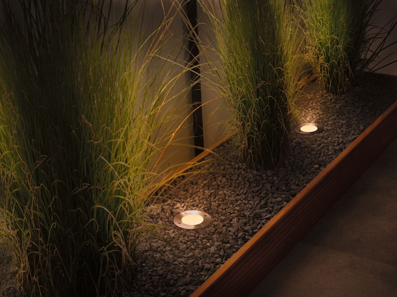 De petites lumières éclairent le gravier et l'herbe.