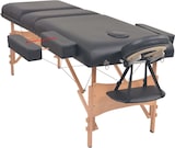 Ein schwarzer Massagetisch mit Holzbeinen.
