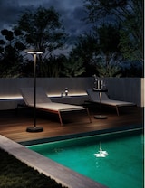 Zwei Liegestühle am Pool bei Nacht.