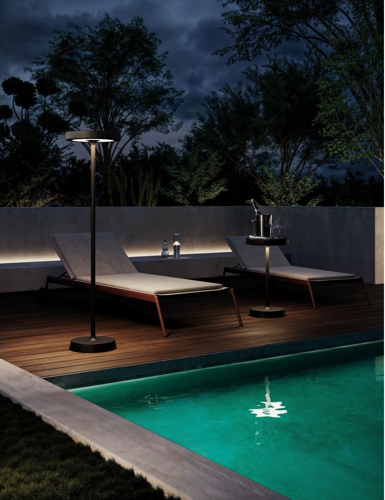 Zwei Liegestühle am Pool bei Nacht.
