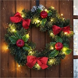 Ein beleuchteter Weihnachtskranz mit roten Schleifen und Äpfeln.