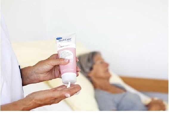 Eine Hand hält eine Tube mit Creme über einer anderen Hand.