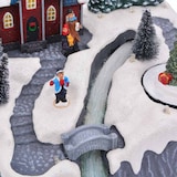 Eine Miniatur-Weihnachtslandschaft mit Figuren und Bäumen.