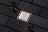 Un luminaire carré encastré éclairé au sol.