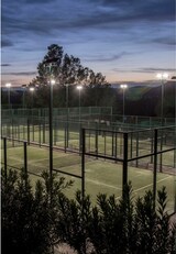 Beleuchtete Tennisplätze bei Dämmerung.