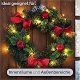 Ein Kranz mit roten Schleifen und Lichtern.