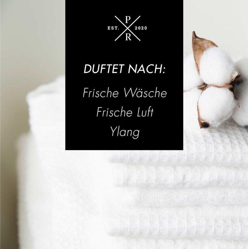 Ein Stapel weißer Handtücher mit Baumwollzweigen.