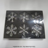 Sei ornamenti scintillanti a forma di fiocco di neve in una scatola.