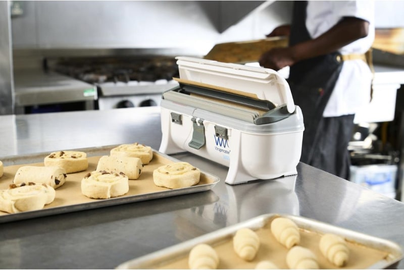 Uma pessoa está embalando produtos assados em uma cozinha profissional.