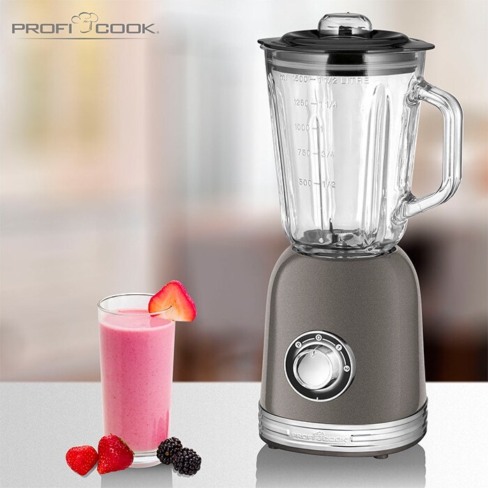 Um liquidificador com um copo de smoothie e frutas.