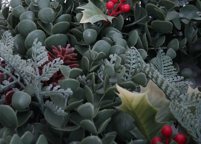 Ein künstlicher Weihnachtskranz mit Beeren und Tannenzapfen.