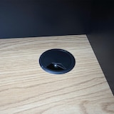 Un passacavo nero su una scrivania di legno.