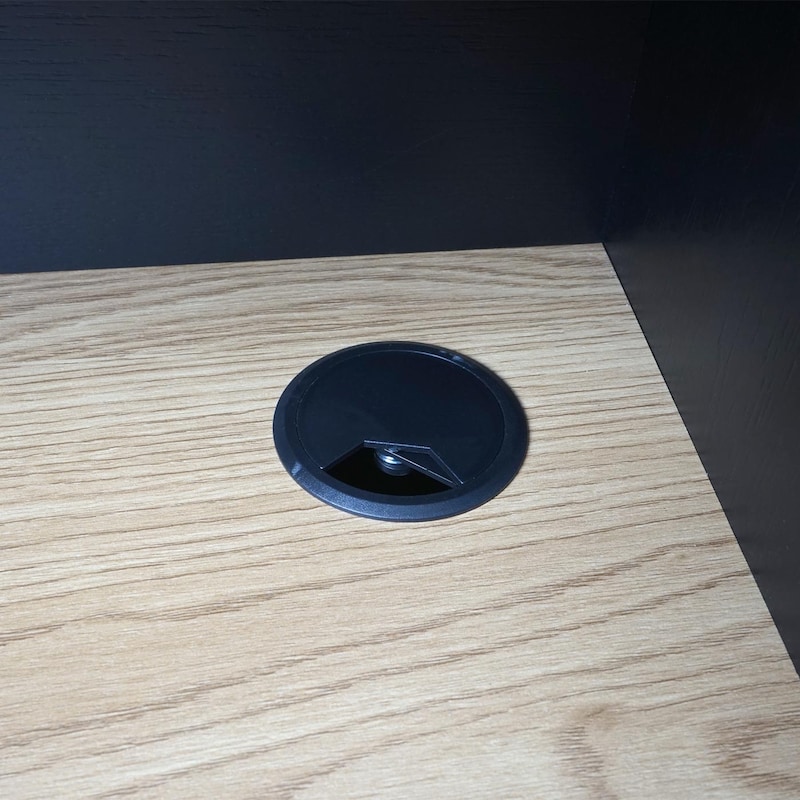 Un passacavo nero su una scrivania di legno.