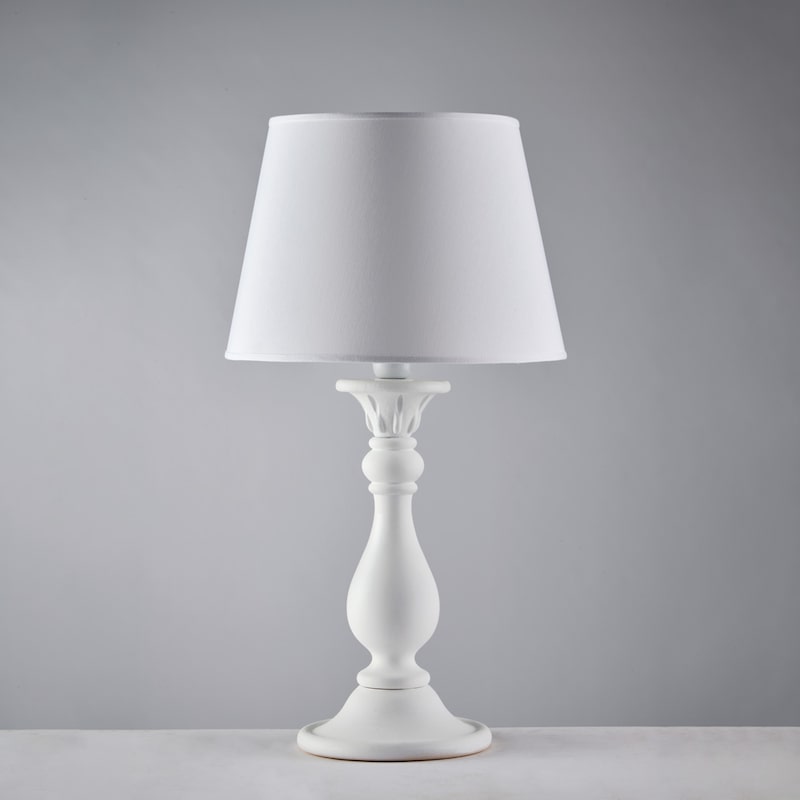 Eine weiße Tischlampe mit einem Lampenschirm.