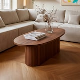 Une table ovale en bois avec livres et vase.