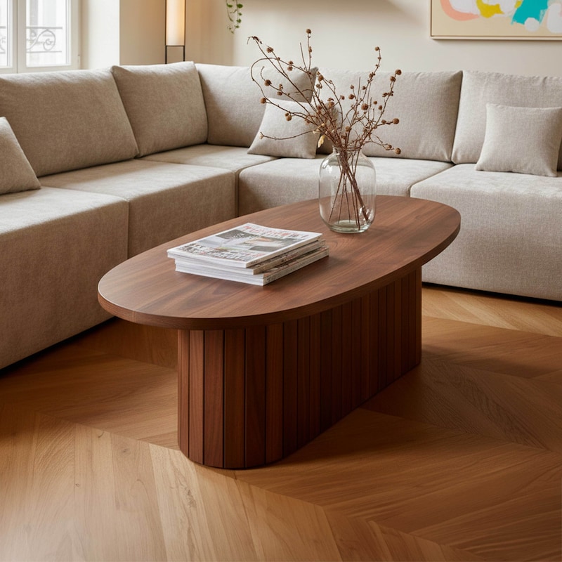 Une table ovale en bois avec livres et vase.