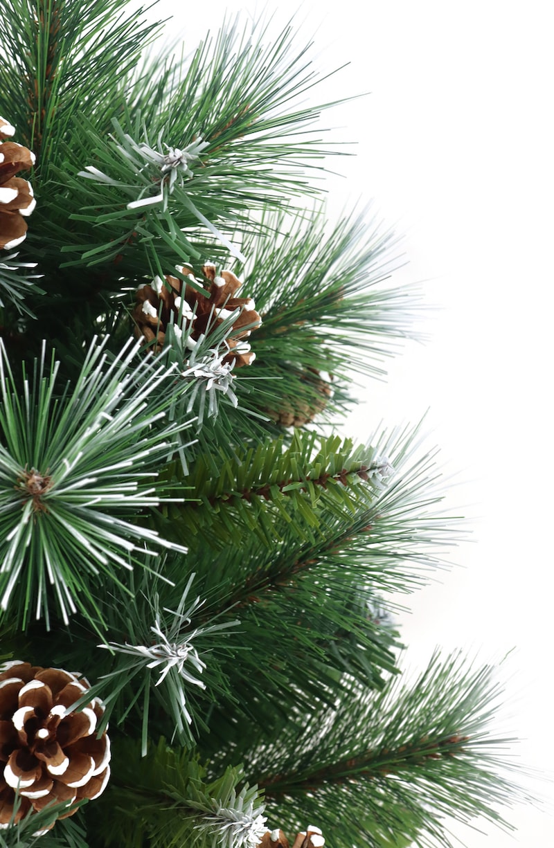 Albero di Natale verde con pigne e neve.
