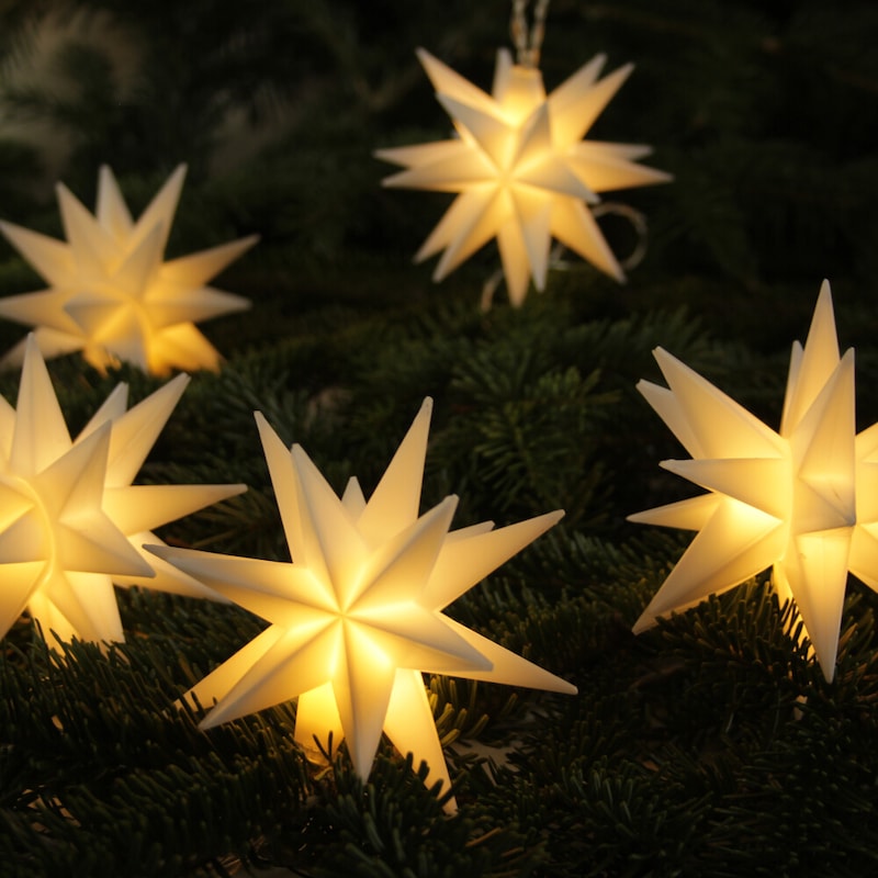Sternförmige Lichterketten auf Tannenzweigen.