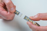 Zwei Hände verbinden LED-Streifen.