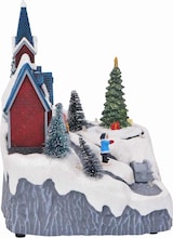 Ein weihnachtliches Dorf mit einer Kirche und einem Baum.