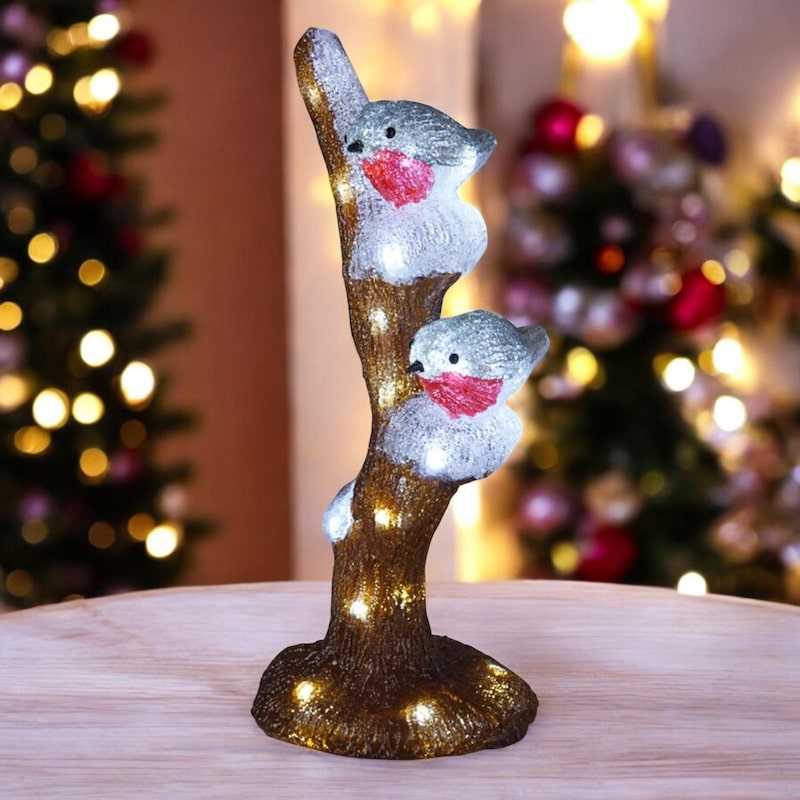 Zwei beleuchtete Vögel auf einem Baumstamm.