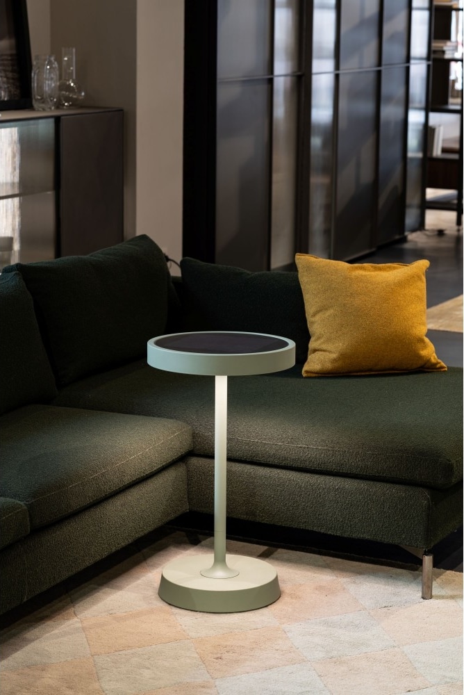 Eine kleine Lampe steht neben einem Sofa.