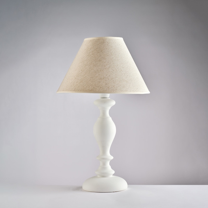 Eine weiße Lampe mit einem beigen Lampenschirm.