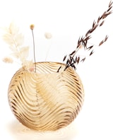 Eine goldene Glasvase mit Wellenmuster und Trockenblumen.