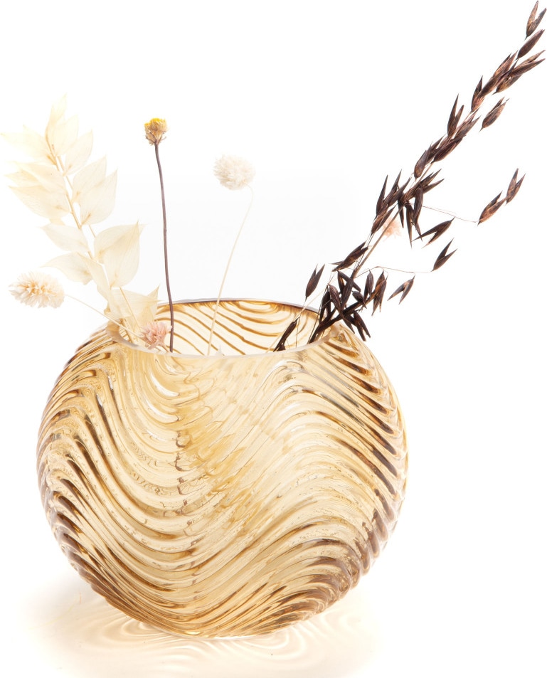 Eine goldene Glasvase mit Wellenmuster und Trockenblumen.