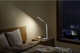 Eine Nachttischlampe beleuchtet ein Bett.
