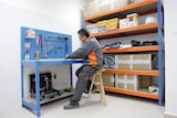 Ein Mann sitzt an einem Werkstatttisch mit Werkzeugen.