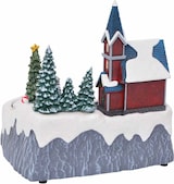 Ein weihnachtliches Dorf mit Kirche und Bäumen.