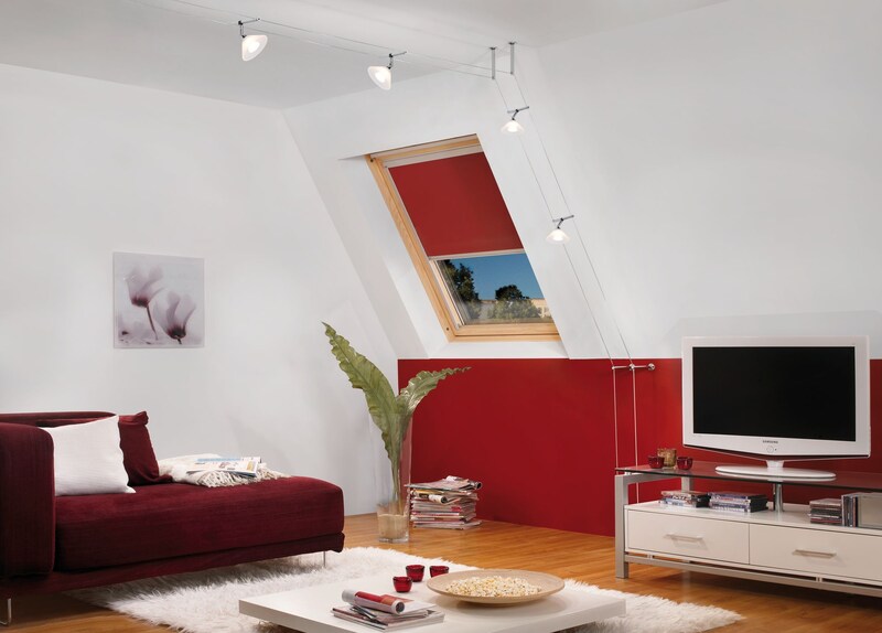 Eine rote Couch mit weißen Kissen und einem Tisch.