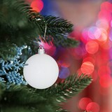 Eine weiße Kugel hängt an einem Weihnachtsbaum.