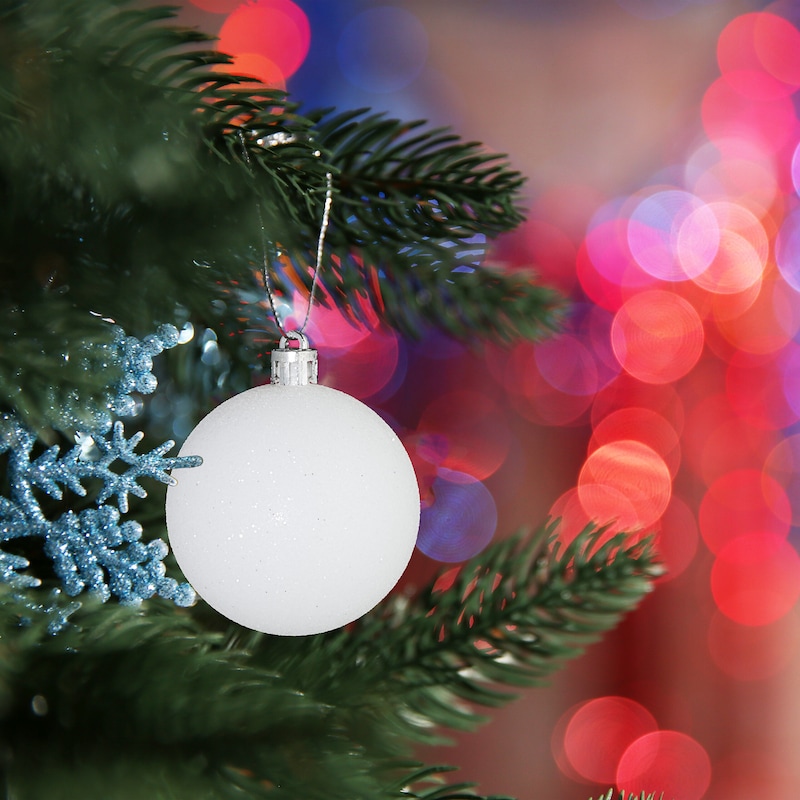 Eine weiße Kugel hängt an einem Weihnachtsbaum.