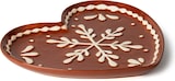 Ein brauner, herzförmiger Teller mit Schneeflocke.