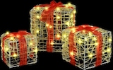 Drei beleuchtete Geschenkboxen mit roten Schleifen.