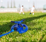 Ein blauer Rasensprenger auf einem Fußballfeld.