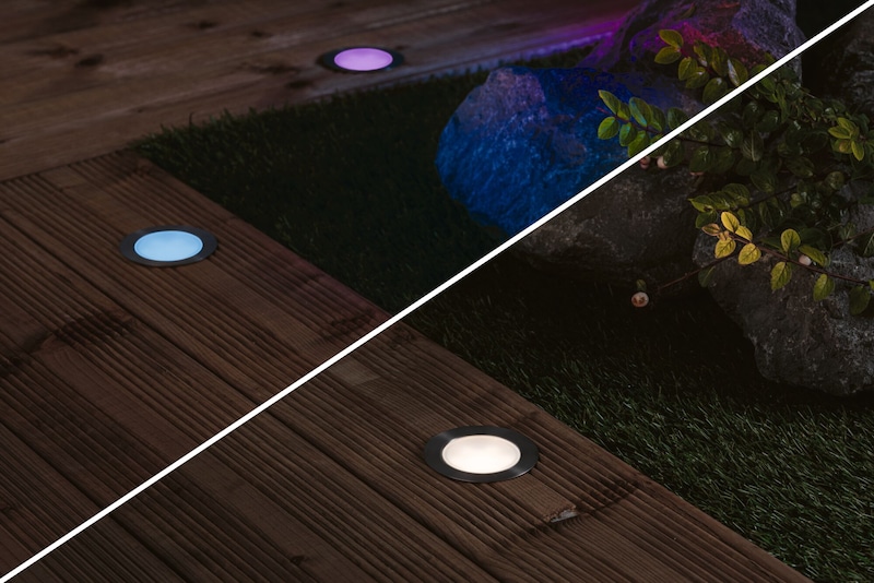 Éclairages de sol changeant de couleur sur bois et gazon.