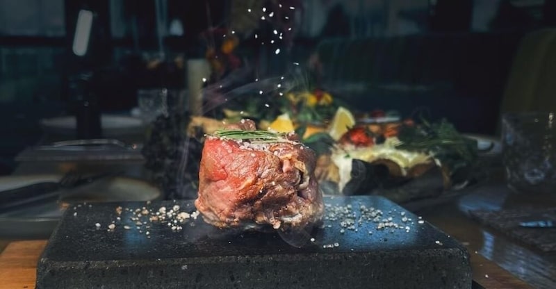 Ein Steak wird auf einem heißen Stein zubereitet.