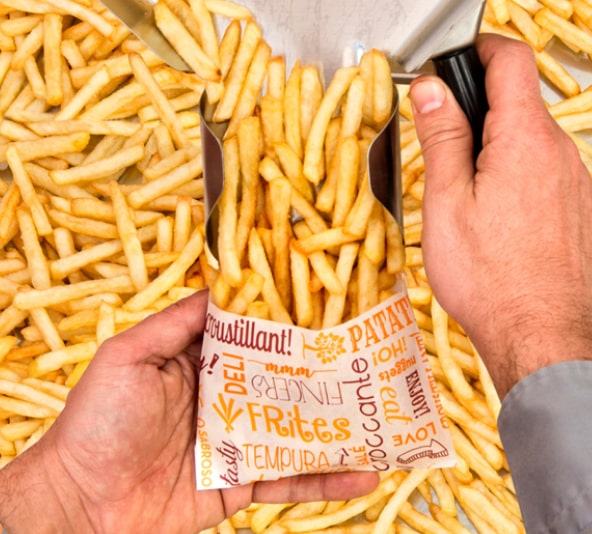 Uma pessoa enche um saco de papel com batatas fritas.