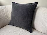 Ein dunkles Kissen auf einem Sofa.