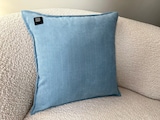Ein blaues Kissen auf einer Couch.