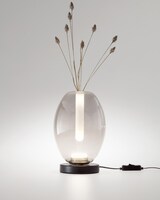 Eine Vase mit einem Licht und getrockneten Pflanzen.