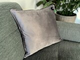Ein graues Kissen auf einem Sofa.